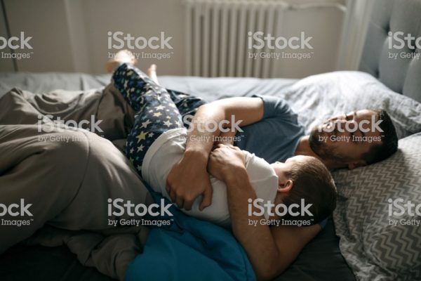 Father and son playing in bed, the having their good morning Father and son playing in bed, the having their good morning